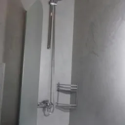 Nowoczesna łazienka z wanną, szklanym parawanem nawannowym i chromowaną armaturą na tle ściany w odcieniach szarości z efektem dekoracyjnym.