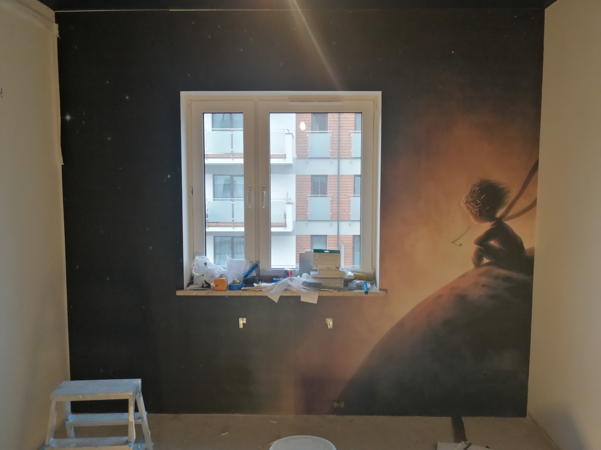 Pokój po malowaniu, ściana z motywem Małego Księcia, widoczne narzędzia i drabina malarska