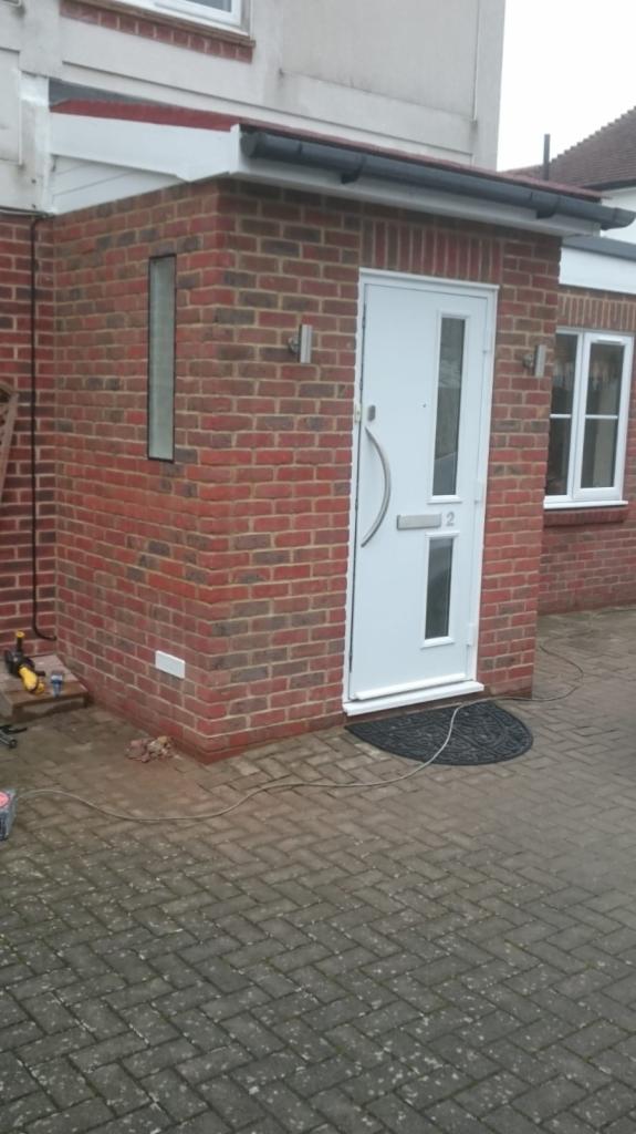 Nowo wybudowane wejście do domu z cegły w Morden, z białą stolarką drzwiową i okienną oraz numerem domu '2' nad skrzynką pocztową.