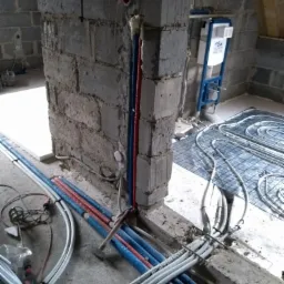 Wewnętrzna instalacja rur wodnych (czerwone i niebieskie) oraz szarych rur kanalizacyjnych, widoczna instalacja podtynkowa WC oraz fragment instalacji ogrzewania podłogowego na poddaszu w trakcie...