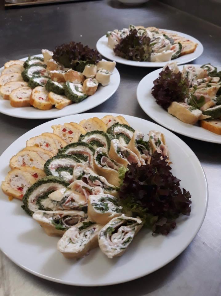 Trzy białe talerze z roladkami mięsnymi i warzywnymi, udekorowane ciemną sałatą na metalowym blacie.