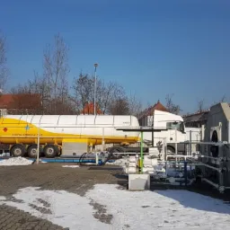 Cysterna w barwach żółto-białych South Stream CAZ na tle instalacji przemysłowej i błękitnego nieba.