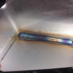 Połączenie spawane dwóch elementów z blachy nierdzewnej, widoczne charakterystyczne przebarwienia po spawaniu TIG.