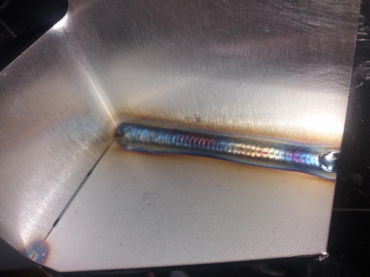 Połączenie spawane dwóch elementów z blachy nierdzewnej, widoczne charakterystyczne przebarwienia po spawaniu TIG.