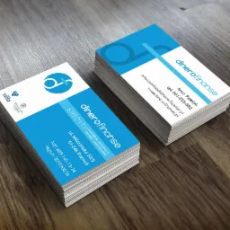 Stos wizyt&oacute;wek firmy Dinero Finanse z logo i informacjami kontaktowymi, oferującej kredyty got&oacute;wkowe, hipoteczne, firmowe i samochodowe, leżące na drewnianym blacie.