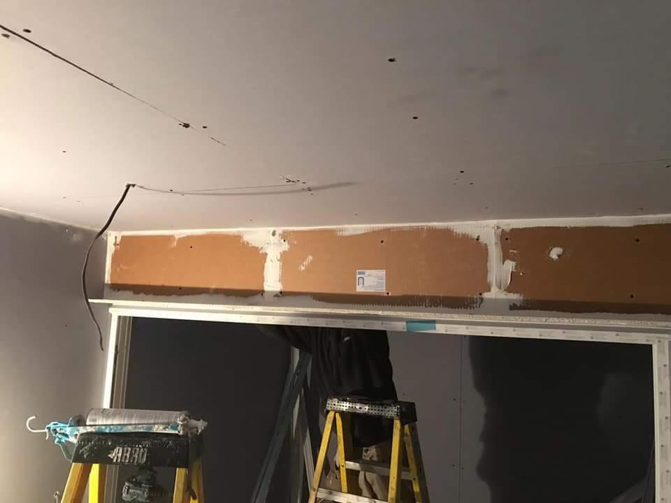 Montaż konstrukcji pod zabudowę sufitu, widoczne profile i częściowo zamontowane płyty, drabina i narzędzia w pomieszczeniu w trakcie remontu.