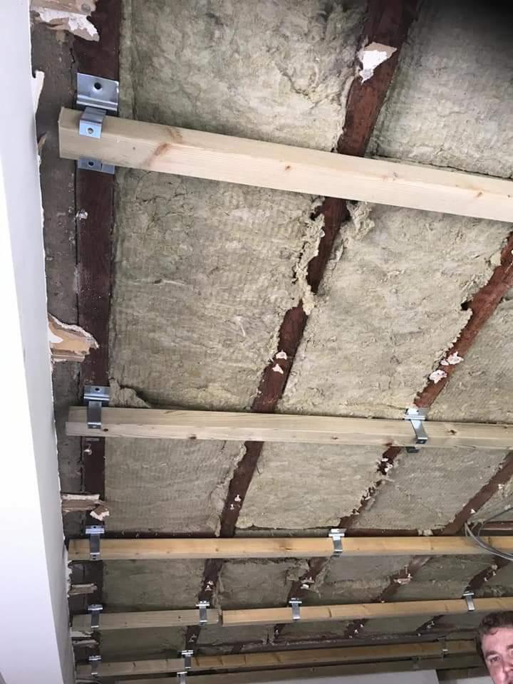 Montaż drewnianej konstrukcji pod izolację sufitu z wełny mineralnej w Aleksandrowie Łódzkim, widoczne metalowe uchwyty mocujące.