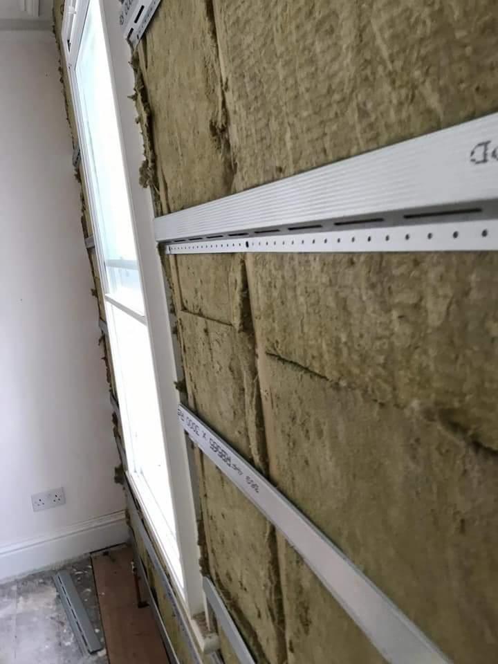 Montaż izolacji z wełny mineralnej pod płytę kartonowo-gipsową, widoczne profile montażowe przy oknie.