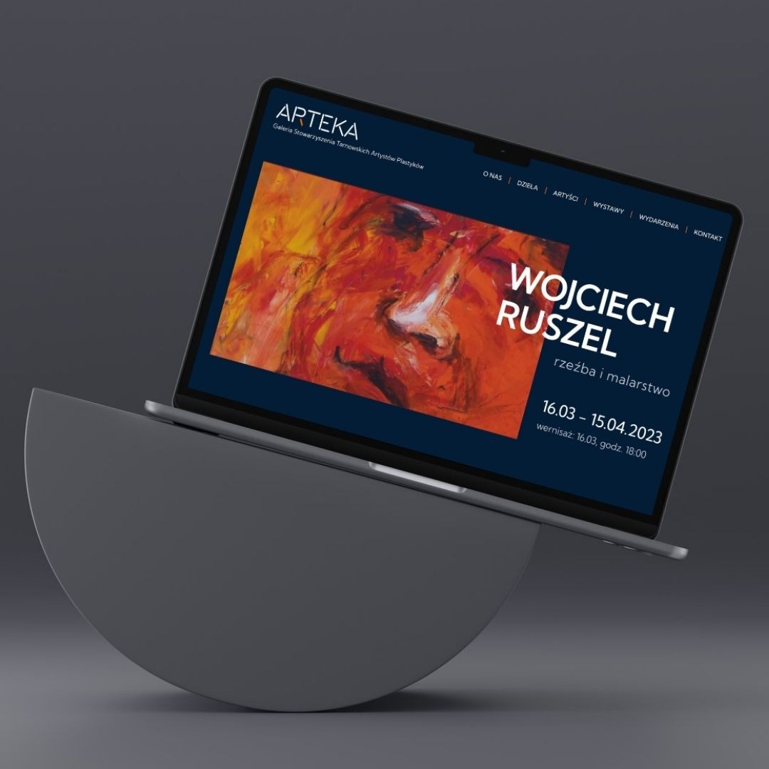 Laptop prezentuje stronę internetową galerii sztuki ARTEKA z wystawą Wojciecha Ruszela. Abstrakcyjny obraz w tle, menu nawigacyjne. Minimalistyczny design, szare tło.