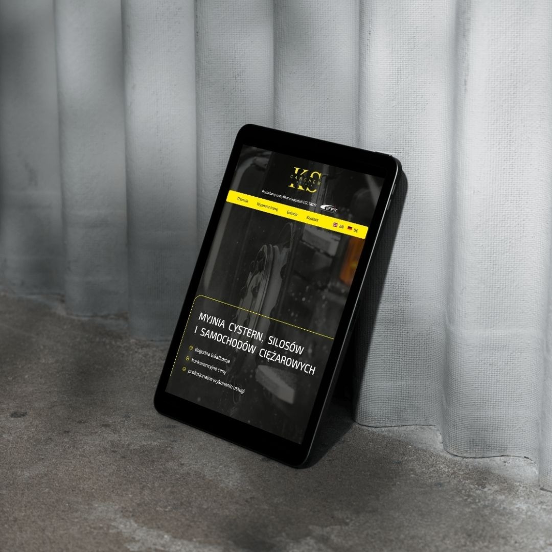 Tablet prezentuje stronę internetową firmy myjącej cysterny i silosy. Minimalistyczny design, ciemna kolorystyka, czytelne menu. Tablet oparty o szarą ścianę.