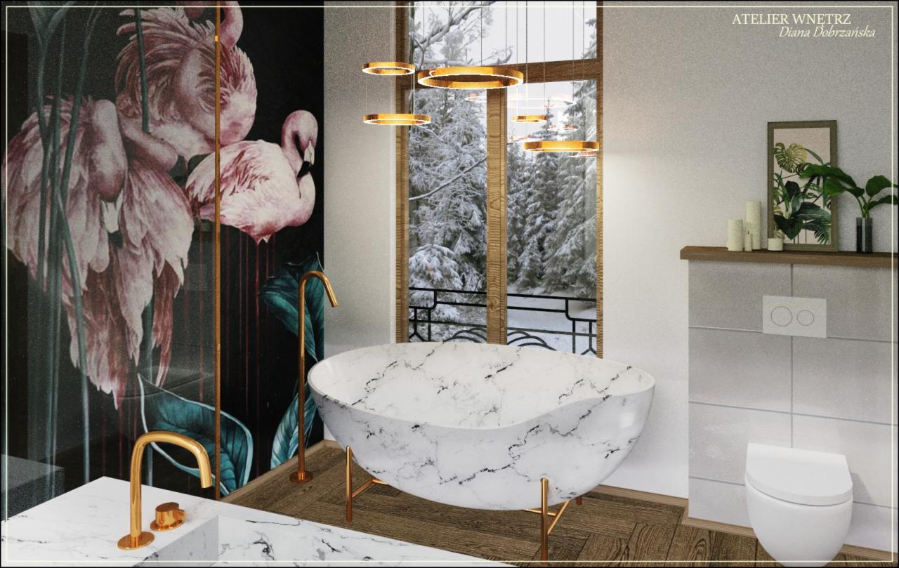 Luksusowa łazienka z wolnostojącą wanną z marmurowym wzorem, złotymi nogami i baterią, na tle okna z widokiem na zimowy las, a na ścianie tapeta z motywem flamingów.