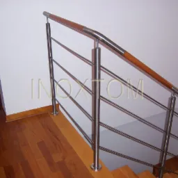 Nowoczesne schody z drewnianymi stopniami i balustradą ze stali nierdzewnej z drewnianą poręczą, widoczny fragment podłogi z parkietu.