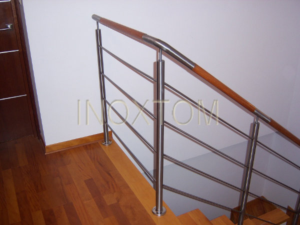 Nowoczesne schody z drewnianymi stopniami i balustradą ze stali nierdzewnej z drewnianą poręczą, widoczny fragment podłogi z parkietu.