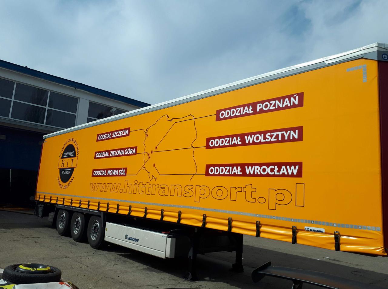 Żółta naczepa ciężarówki z mapą Polski i zaznaczonymi oddziałami firmy transportowej w Poznaniu, Szczecinie, Zielonej Górze, Nowej Soli, Wolsztynie i Wrocławiu oraz adresem strony internetowej.