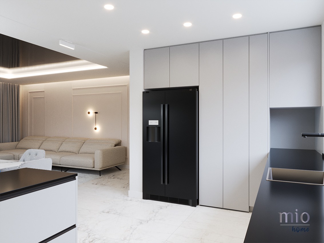 Nowoczesna kuchnia z salonem w tle: czarna lodówka side-by-side w zabudowie, szare szafki kuchenne, marmurowa podłoga, beżowa sofa i designerskie oświetlenie ścienne.