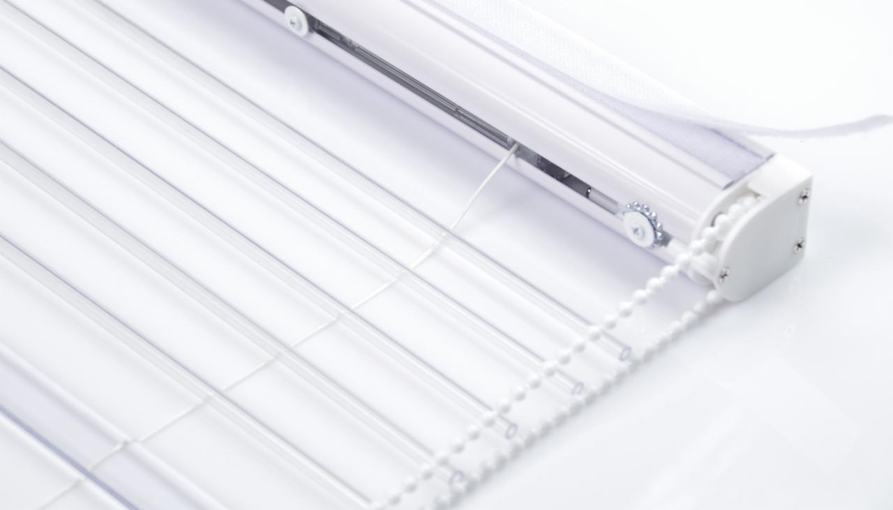 Detaliczne ujęcie białych, transparentnych żaluzji z mechanizmem łańcuszkowym na jasnym tle.