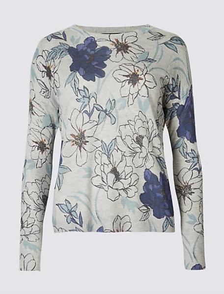 Damski sweter z długim rękawem w kwiatowy wzór, z przewagą szarości, bieli i granatu, na jednolitym jasnoszarym tle.