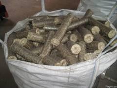 Duży worek wypełniony cylindrycznymi brykietami z biomasy o szarej barwie i widocznej strukturze włókien. Brykiety ułożone są chaotycznie, a worek jest częściowo otwarty.