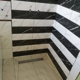 Ułożone w pasy czarno-białe płytki imitujące marmur na ścianie i podłodze łazienki, z widocznym odpływem liniowym i otworami na baterię.