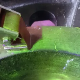 Zbliżenie na fragment instalacji gazowej z widocznymi elementami mocującymi i śladami korozji podświetlonymi na zielono.