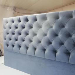 Rafał Tapicer - Wezgłowie łóżka obite szarym, pikowanym aksamitem z głębokimi guzikami, sfotografowane w warsztacie.