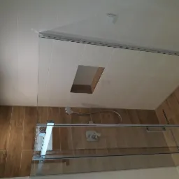 Wykończona łazienka z kabiną prysznicową typu walk-in, drewnopodobnymi płytkami na ścianach i białymi płytkami na suficie z wnęką.