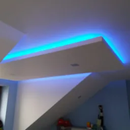 Podwieszany sufit z oświetleniem LED w kolorze turkusowym, widoczne skosy i okno w tle.