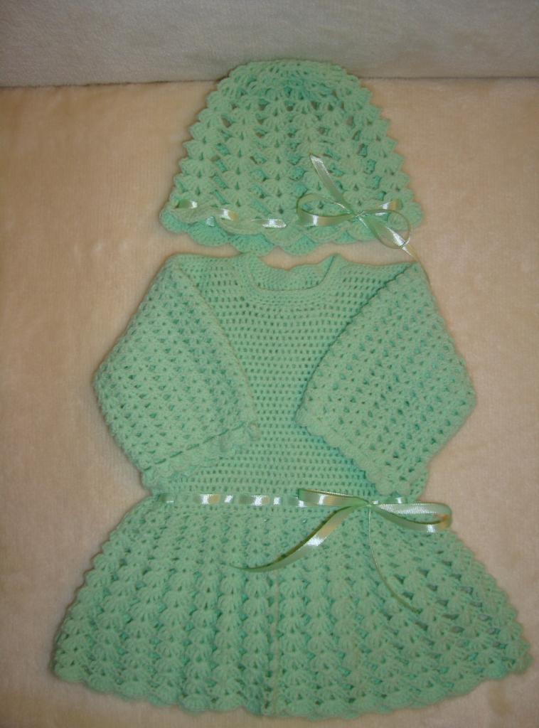 Ręcznie robiony, szydełkowy komplet dla niemowlaka w pastelowym, miętowym odcieniu, składający się z sukienki i czapeczki, ozdobiony satynowymi wstążkami.