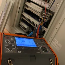 Pomiar rezystancji izolacji w rozdzielnicy elektrycznej za pomocą miernika Sonel MPI-525 z widocznymi przewodami pomiarowymi.