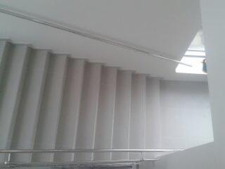 Schody betonowe z metalową balustradą, widok z góry, oświetlenie dzienne, surowy stan wykończenia.