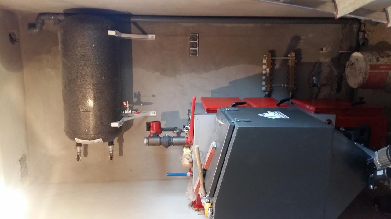 Nowoczesny piec centralnego ogrzewania z zasobnikiem ciepłej wody, zainstalowany w kotłowni w Dorotowie, widoczne rury i armatura.