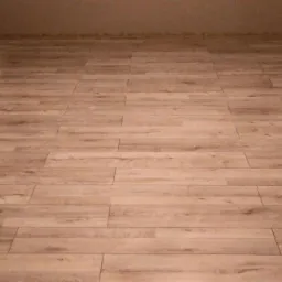 Ułożony parkiet laminowany w jasnym odcieniu drewna, widok na całą podłogę w pomieszczeniu o jasnych ścianach, z widocznym grzejnikiem po lewej stronie.