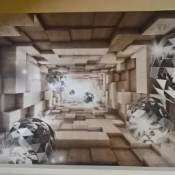 Tapeta z motywem trójwymiarowego tunelu z drewnianych bloków i geometrycznych kul, oświetlona światłem wpadającym przez okno po lewej stronie.