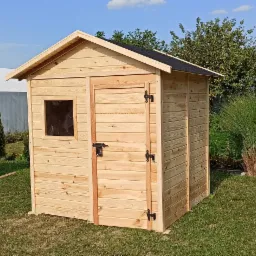 Drewniana budka ogrodowa z oknem i drzwiami na tle zielonego trawnika i ogrodu.