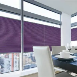 Fioletowe plisy okienne w nowoczesnej jadalni z widokiem na miasto, częściowo zasłonięte, widoczne nakrycia stołowe.