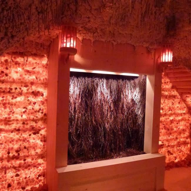 Tężnia solankowa wewnątrz pomieszczenia z oświetleniem w kolorze czerwonym, ściany wyłożone solą.