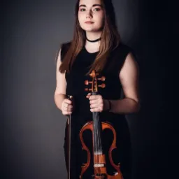 Portret młodej kobiety w czarnej sukience, trzymającej skrzypce elektryczne i smyczek na ciemnoszarym tle.