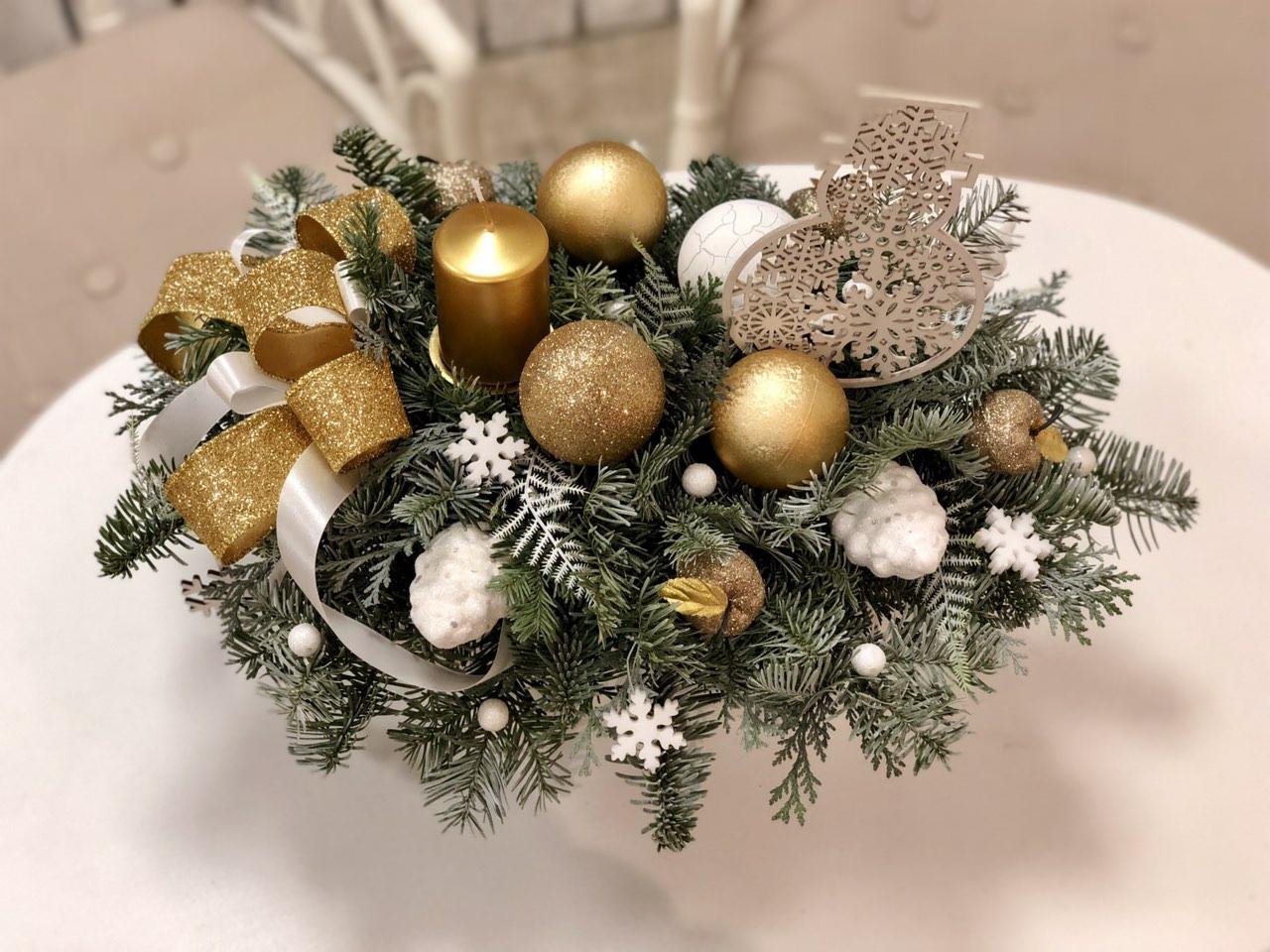 Świąteczna kompozycja stroikowa z zielonych gałązek, złotych bombek, świecy i dekoracji śnieżynek, wykonana we Wrocławiu.
