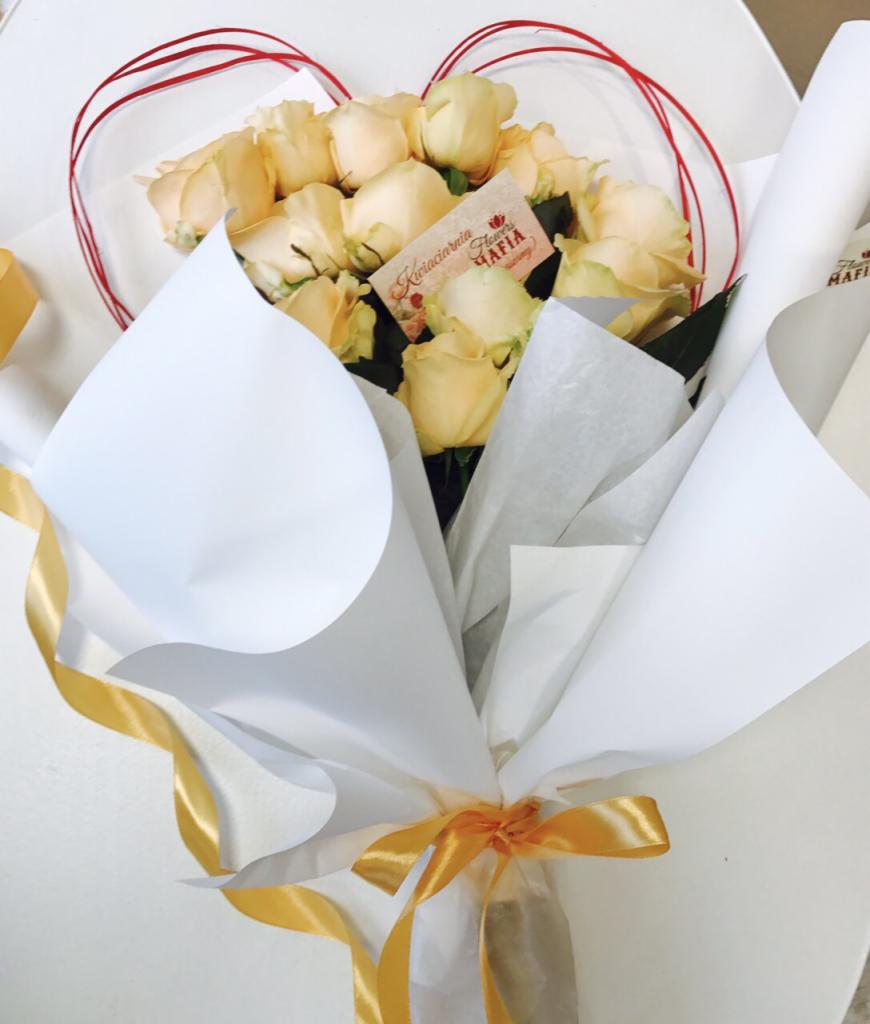 Bukiet jasnych róż w białym papierze z czerwoną ramką w kształcie serca i złotą wstążką, etykieta z napisem 'Kwiaciarnia Flowers MAFIA'