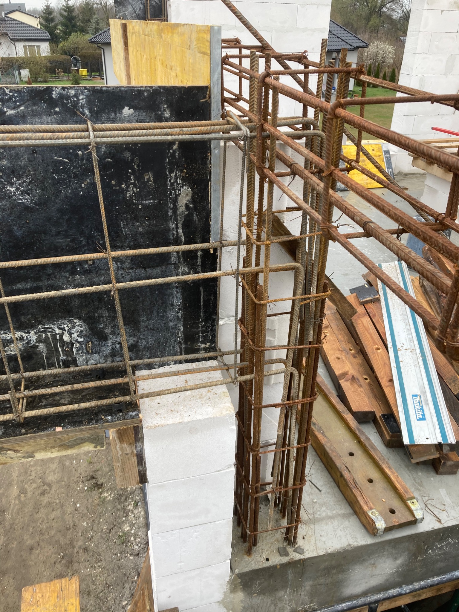 Wznoszenie ściany z bloczków betonu komórkowego Ytong, z widocznym zbrojeniem pionowym i szalunkiem, przygotowanie do zalewania betonem.