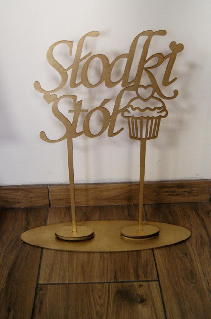 Drewniany, złoty napis 'Słodki Stół' z grafiką babeczki na stojaku, dekoracja na przyjęcie.