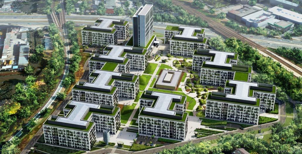 Wizualizacja osiedla nowoczesnych budynków wielorodzinnych z zielonymi dachami, widok z lotu ptaka, w tle linia kolejowa i zabudowa miejska.