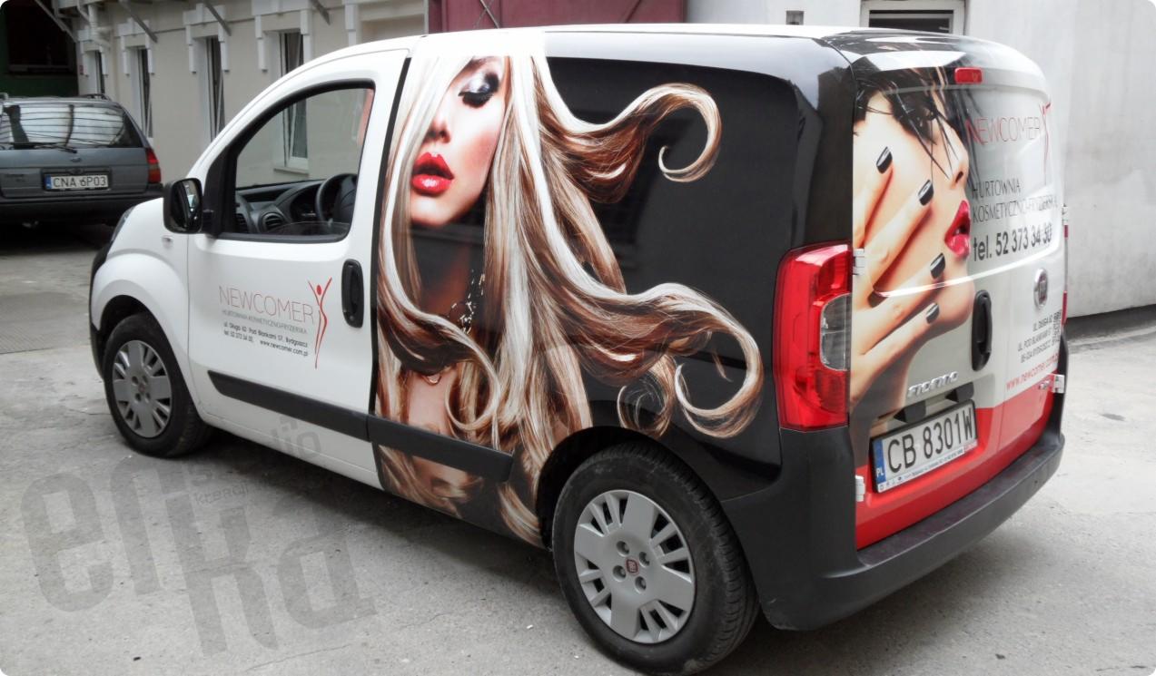 Biały samochód dostawczy oklejony grafiką reklamową salonu kosmetycznego z wizerunkiem kobiety z blond włosami i dłoni z czarnym manicure.