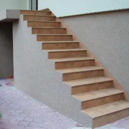 Zewnętrzne schody z terakoty prowadzące do budynku, z widoczną fakturą elewacji i brukowanym chodnikiem