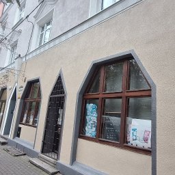F.H.U MIESZBUD Grzegorz Mieszalski - Elewacja kamienicy z oknami w kształcie łuku, widok z chodnika. Na elewacji widoczna rynna spustowa. Uwagę zwracają nietypowe okna i kolorystyka budynku.