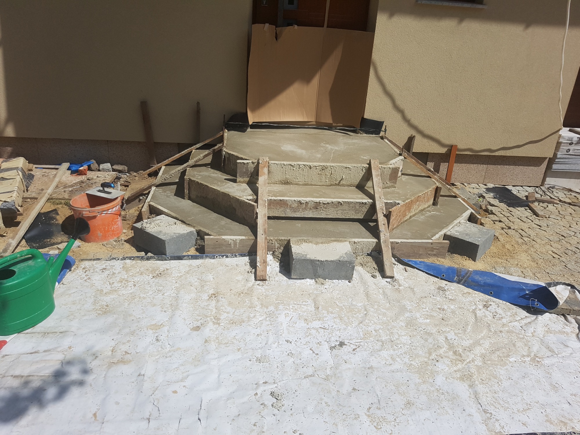 W Starym Jaworowie widać budowę betonowych schodów wejściowych do domu, z drewnianym szalunkiem i przygotowanymi blokami betonowymi, na podłożu zabezpieczonym folią. W tle widoczne narzędzia...