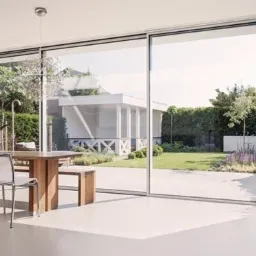 Nowoczesne wnętrze z przesuwnymi, panoramicznymi oknami aluminiowymi, widok na ogród z białym pawilonem, minimalistyczny design z drewnianym stołem i kominkiem.