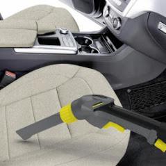 Czyszczenie beżowego fotela samochodowego odkurzaczem parowym z żółtymi elementami, widoczny kokpit pojazdu.