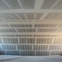 LUC-BAR - Sufit z płyt kartonowo-gipsowych, szpachlowany, widok z dołu, z perspektywą zbieżną. Widoczne łączenia płyt i szpachlowane miejsca wkrętów.