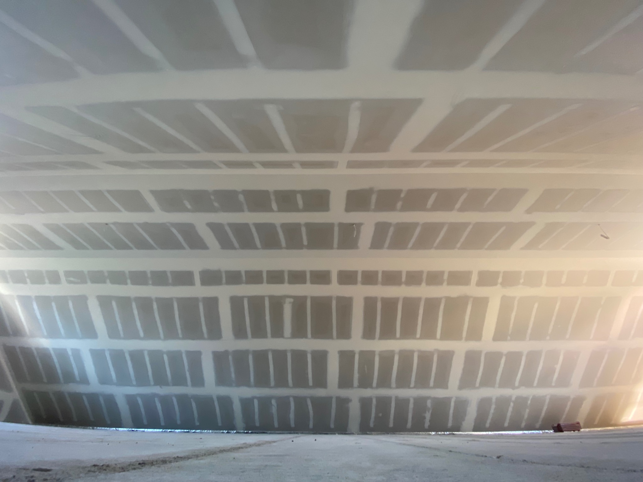Sufit z płyt kartonowo-gipsowych, szpachlowany, widok z dołu, z perspektywą zbieżną. Widoczne łączenia płyt i szpachlowane miejsca wkrętów.
